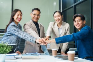 In a boardroom, an Asian team meets at a desk, presenting financial terms and strategies.